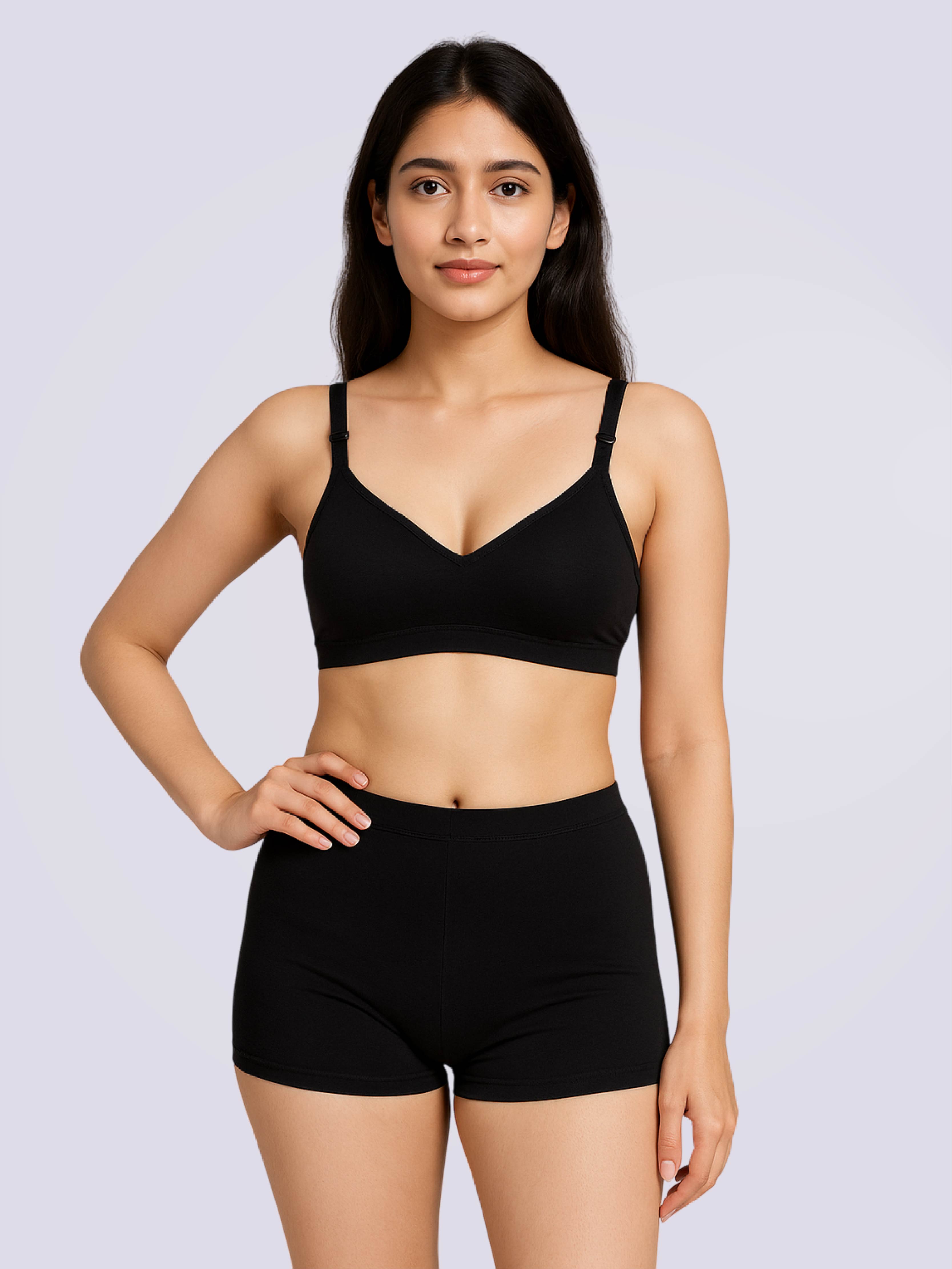 Woman wearing a black sports bra and shorts on a light gray background